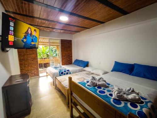 two beds in a room with a tv and a tv at ISA BELLA Hospedaje y Cabaña Entre Aves in Luna Park