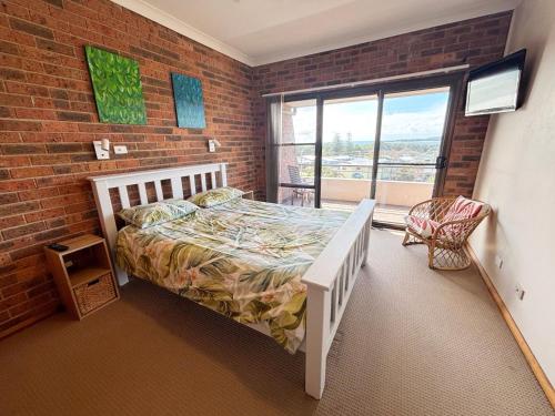 a bedroom with a bed and a brick wall at Seaview Townhouse 2 - Bring your own linen. in South West Rocks