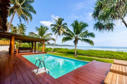 a swimming pool on a deck with the ocean in the background at Marbella Mentawai Beachfront Private Villa Sleeps 10 in Katiet