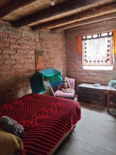 a bedroom with a bed and a chair and a window at casa domo in Maimará
