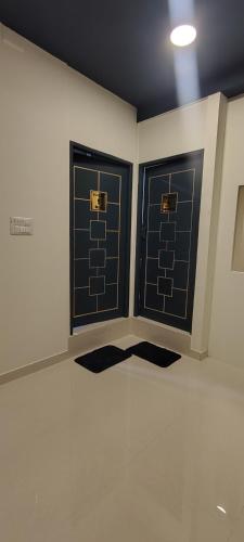 two doors in a room with mats on the floor at Thuyil Inn Koodal in Madurai