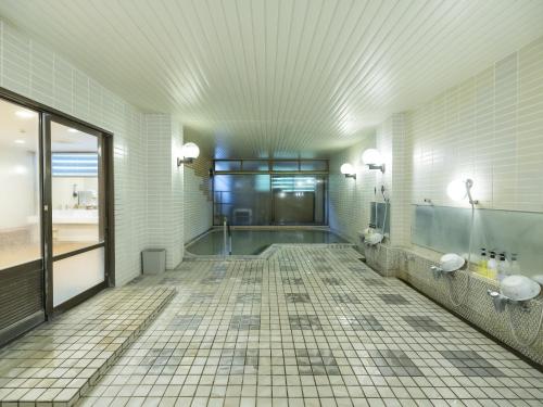 a bathroom with two urinals and a tiled floor at 黒姫高原ホテル in Shinano