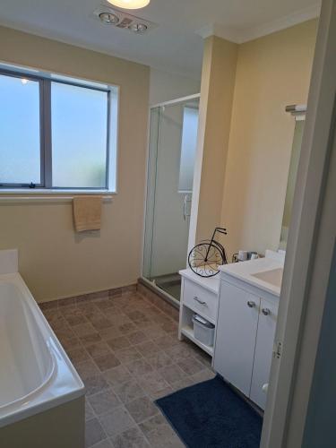 a bathroom with a sink and a shower and a bike at Digs Homestay in Stratford