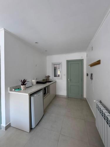 a kitchen with white walls and a green door at Entre Patios in Azul