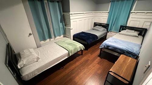 two beds in a small room with blue curtains at Journey House LA in Los Angeles