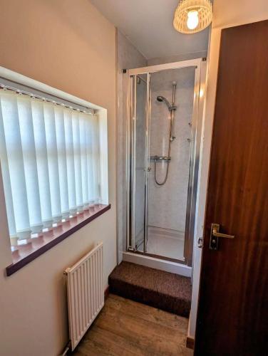 a bathroom with a shower with a glass door at Burnside Holiday Cottage 2 in Fochabers