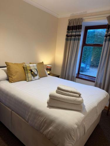 a bedroom with a bed with towels on it at Burnside Holiday Cottage 2 in Fochabers