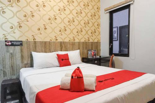 a bedroom with a bed with a red robe on it at RedDoorz @ Bukit Dieng 2 in Malang