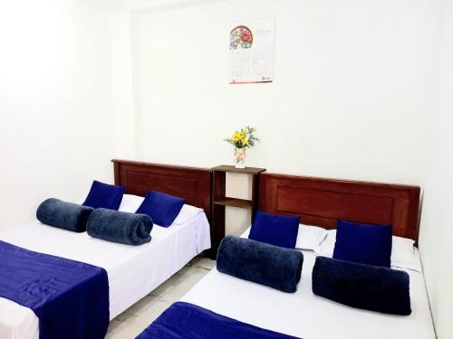 two beds in a room with blue pillows at City Lavish in Nuwara Eliya