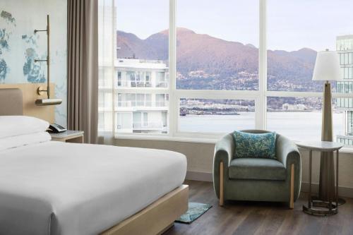 a bedroom with a bed and a chair and a large window at Vancouver Marriott Pinnacle Downtown Hotel in Vancouver