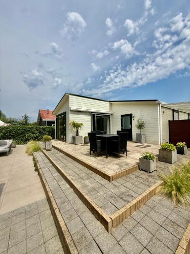 a patio with a black table and chairs on it at Vakantiewoning De Bosrand Aan Zee in Sint Annaland