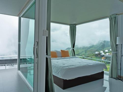a bedroom with a bed and large glass windows at ม่อนทับเบิก รีสอร์ท ภูทับเบิก in Ban Maeo Thap Boek
