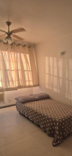 a bed in a room with a ceiling fan at Praia do Forte - AP DA PAZ in Cabo Frio