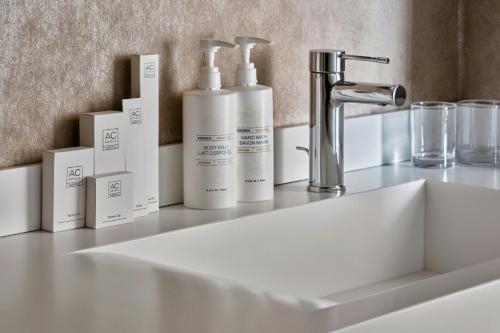 a counter with three bottles ofodorizers and a sink at AC Hotel by Marriott Wroclaw in Wrocław