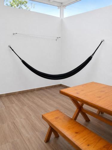 a hammock in a room with a table and a bench at Descanse perto do aeroporto e Conheça Maceió - 24h in Maceió