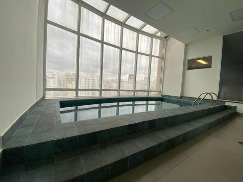 a swimming pool in a building with a large window at Flat Parque do Ibirapuera - Jardins in São Paulo