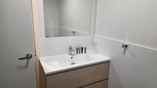 a white bathroom with a sink and a mirror at Alpinwood in Dinner Plain
