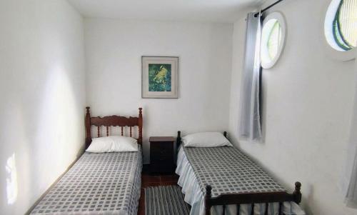 two beds in a room with white walls at Apartamento dos Arcos in Teresópolis