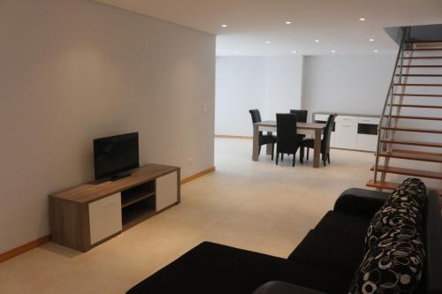 a living room with a couch and a television at Cantinho Das Praias in Vila Franca do Campo