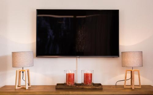 two lamps on a table with a television on a wall at Chalet Les Rahâs by Mrs Miggins in Grimentz