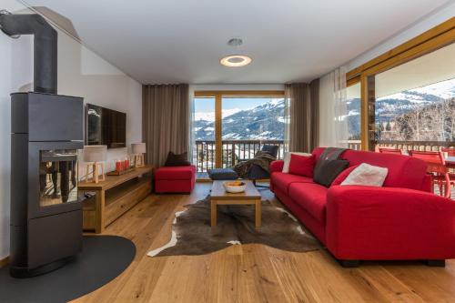 a living room with a red couch and a fireplace at Chalet Les Rahâs by Mrs Miggins in Grimentz
