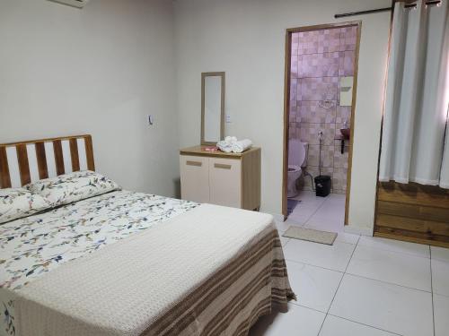a bedroom with a bed and a bathroom with a mirror at Casa da Brisa in Salinópolis