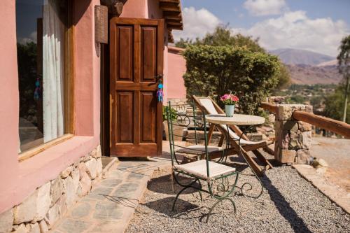 a table and chairs on a balcony with a door at Villa del Cielo in Tilcara