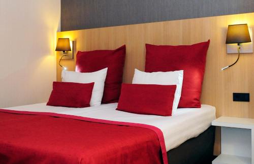 a bedroom with a red and white bed with red pillows at Mercure Hotel Schiphol Terminal in Schiphol