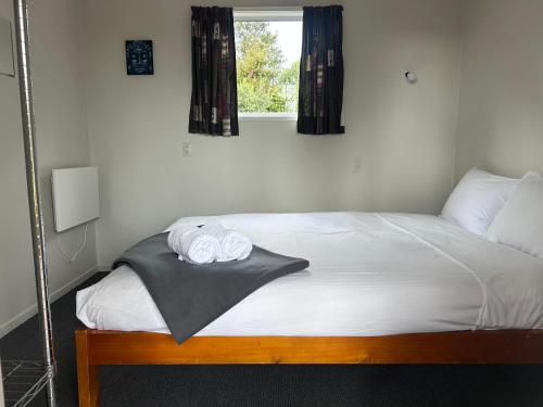 a bedroom with a bed with two towels on it at Tongariro Holiday Park in Tongariro