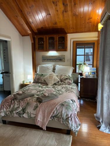 a bedroom with a large bed with a wooden ceiling at Coppabella Cottage in Jingellic