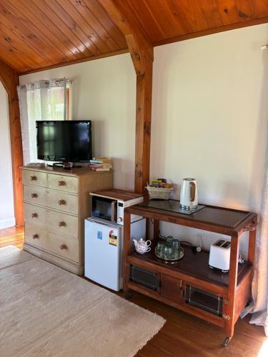 a living room with a television and a refrigerator at Coppabella Cottage in Jingellic
