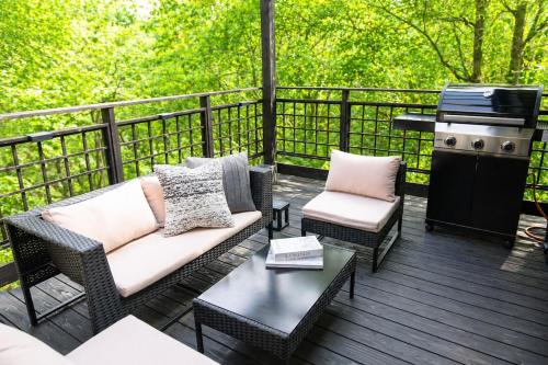 a patio with a couch and chairs and a grill at 源泉かけ流し温泉貸切別荘 霧島のテラス in Kirishima