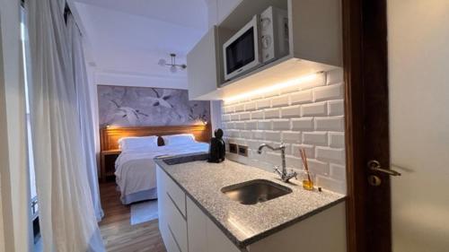 a bathroom with a bedroom with a bed and a sink at Le Flâneur Boutique Hotel in Pergamino