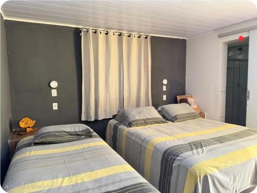 a bedroom with two beds and a window at Quarto privativo Pousada Luna in Fernando de Noronha