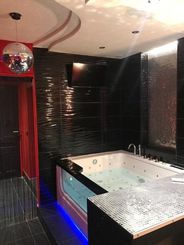 uma casa de banho com uma grande banheira com azulejos pretos em Le Cabaret Vip SPA em Lyon