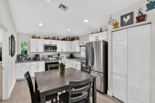 a kitchen with white cabinets and a table with chairs at Abi's House - Private Jupiter Escape in Jupiter