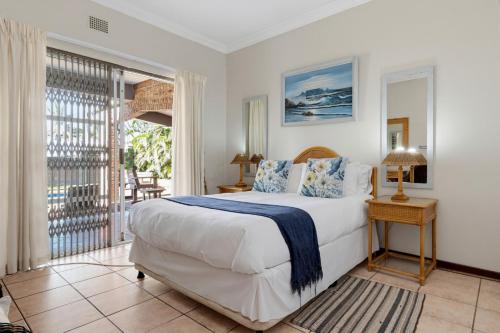 a bedroom with a large bed and a balcony at Palm View in Ballito
