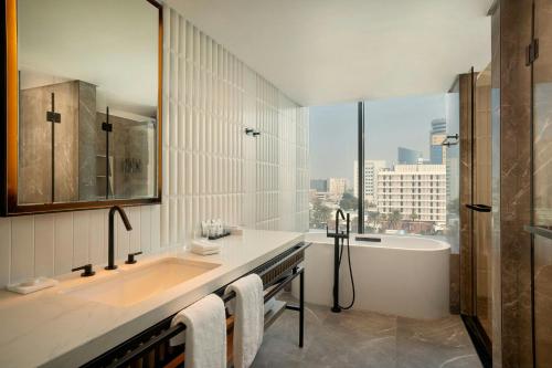 a bathroom with a sink and a bath tub and a window at Sheraton Bahrain Hotel in Manama