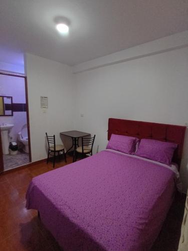 a bedroom with a purple bed with a table and chairs at Hospedaje Miramar in Máncora