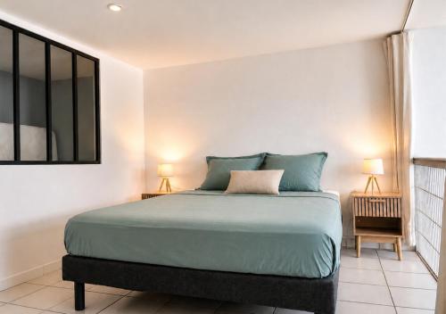 a bedroom with a bed with blue pillows and a mirror at Le Palmier Bleu, Spacious Duplex with Pool in Schœlcher