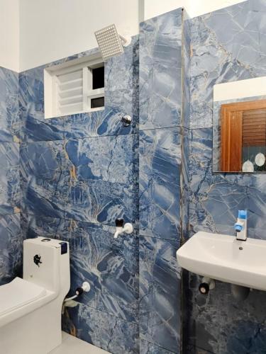 a blue tiled bathroom with a toilet and a sink at La Paraso Agatti in Agatti
