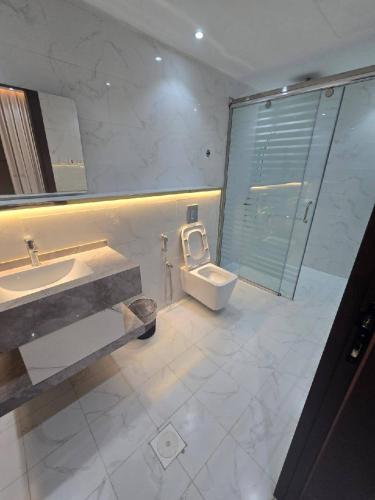 a bathroom with a toilet and a sink and a shower at شالية ورد in Rayyis
