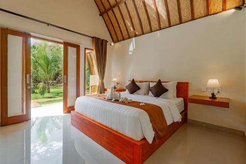 a bedroom with a large bed and a large window at The Kaci Penida By Bali Cabin in Nusa Penida