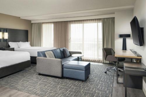 a hotel room with a bed and a bed and a couch at Residence Inn by Marriott Montreal Airport in Dorval