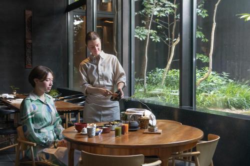 a woman standing next to a table in a restaurant at Sowaka in Kyoto
