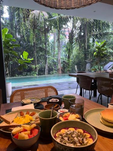 a wooden table with plates of food on it at The CIVYT in Ubud