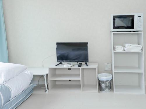 a white bedroom with a desk with a computer on it at ホテルステイ伊万里 in Imari