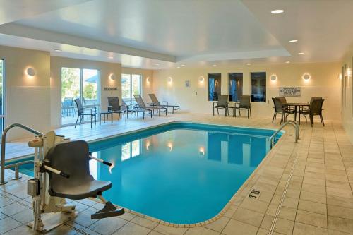 a swimming pool with chairs and tables in a room at Fairfield Inn & Suites Cleveland Avon in Avon