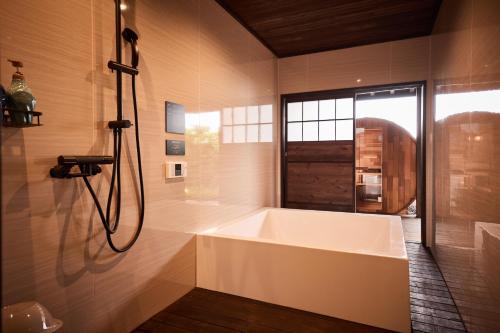 a white bath tub in a bathroom with a window at いっぺ The Sake Ryokan in Kyonan