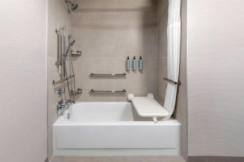 a bathroom with a tub with a toilet and a shower at Courtyard by Marriott Pittsburgh Airport in Coraopolis